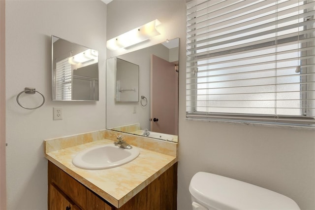 bathroom with vanity, a healthy amount of sunlight, and toilet