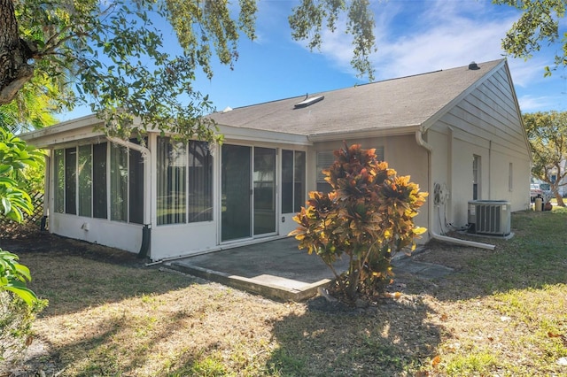 rear view of house featuring a lawn, central AC unit, a patio area, and a sunroom