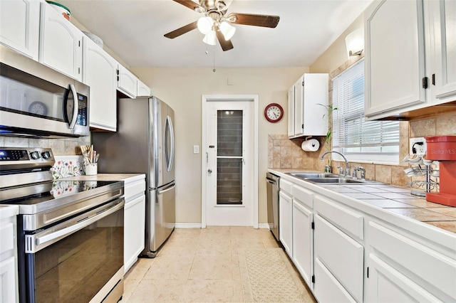 kitchen featuring white cabinetry, sink, decorative backsplash, tile counters, and stainless steel appliances