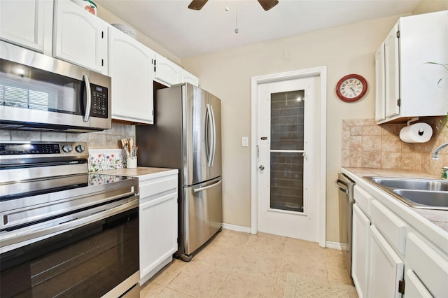 kitchen with appliances with stainless steel finishes, light countertops, white cabinetry, and a sink