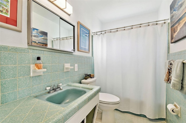 full bathroom featuring curtained shower, toilet, a sink, tile walls, and wainscoting