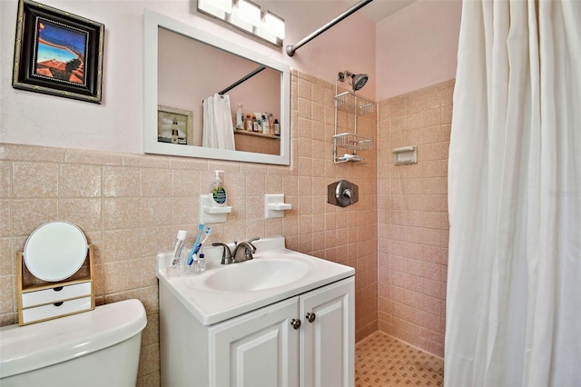 full bathroom featuring toilet, vanity, a tile shower, and tile walls