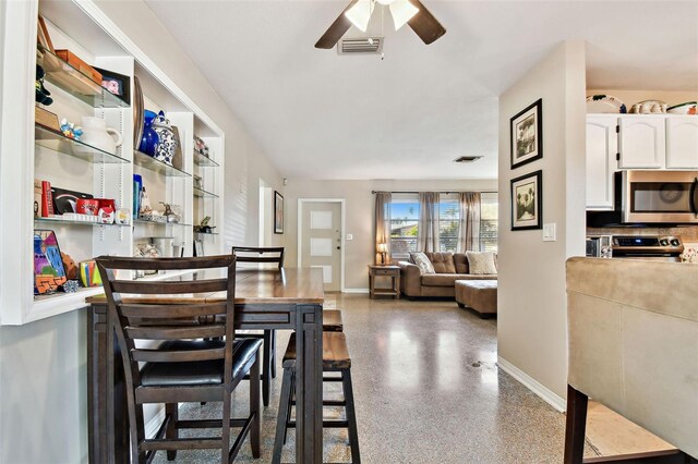 dining space with baseboards, visible vents, a ceiling fan, and speckled floor