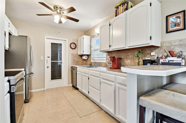 kitchen featuring white cabinets, decorative backsplash, stainless steel appliances, and a sink