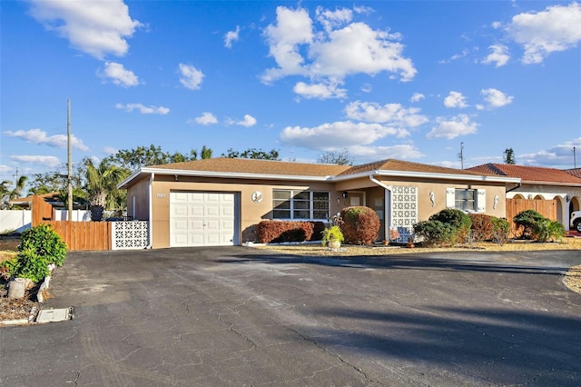 single story home featuring a garage, fence, driveway, and stucco siding