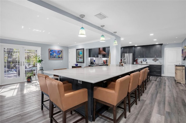 kitchen with light wood-type flooring, stainless steel refrigerator, a large island, and pendant lighting