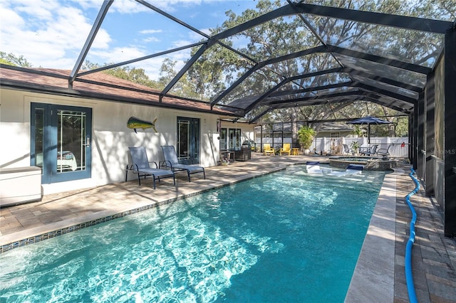 view of pool featuring glass enclosure, an in ground hot tub, and a patio