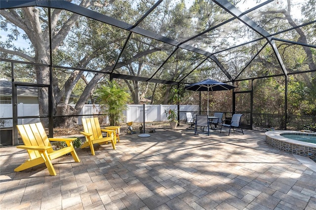 view of patio featuring glass enclosure and an in ground hot tub