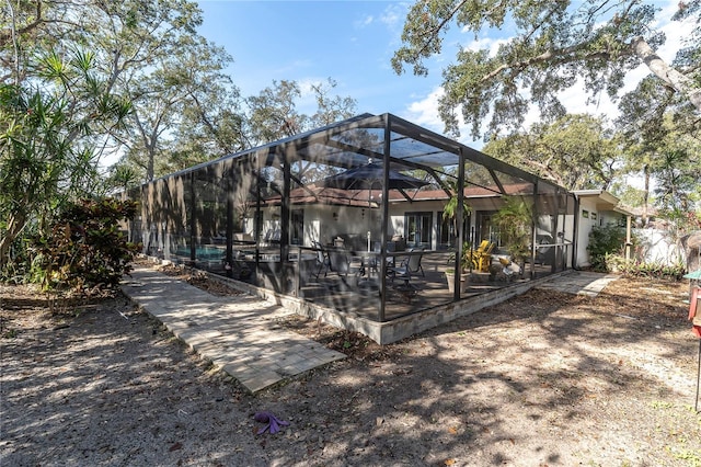 back of property with glass enclosure and a patio