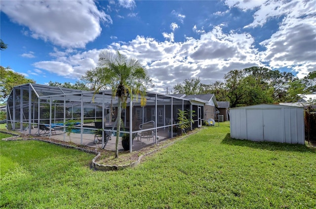 view of yard with glass enclosure, a storage unit, and a patio area