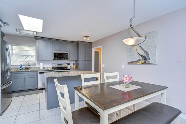 tiled dining space featuring sink and a skylight