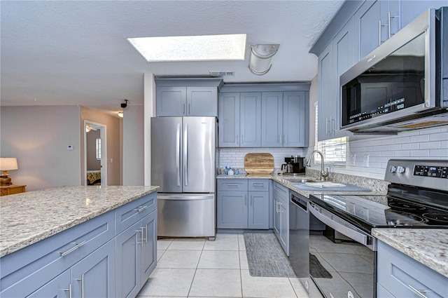 kitchen featuring tasteful backsplash, a skylight, sink, and appliances with stainless steel finishes