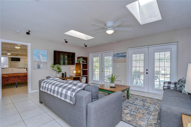 tiled living room featuring french doors, a skylight, and ceiling fan