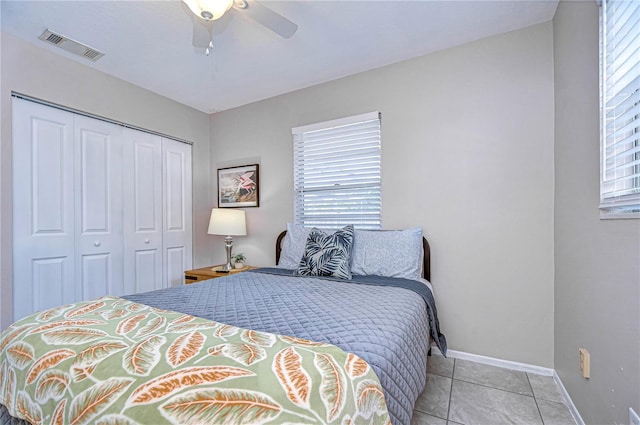 tiled bedroom with ceiling fan and a closet