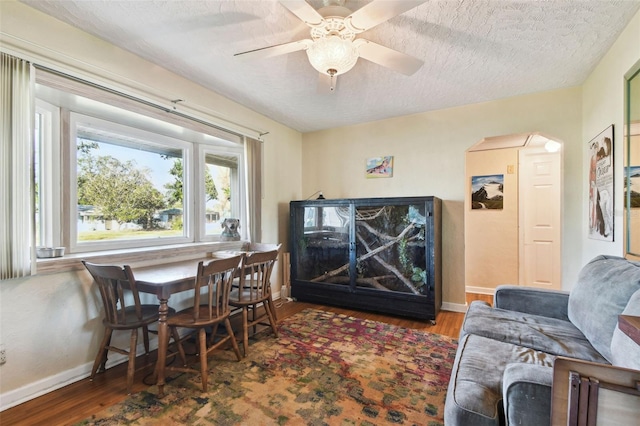 dining room with a textured ceiling, ceiling fan, and dark wood-type flooring