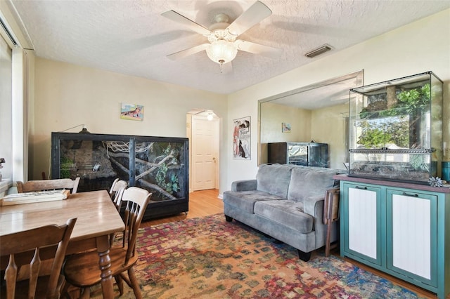 living room featuring hardwood / wood-style floors, a textured ceiling, and ceiling fan