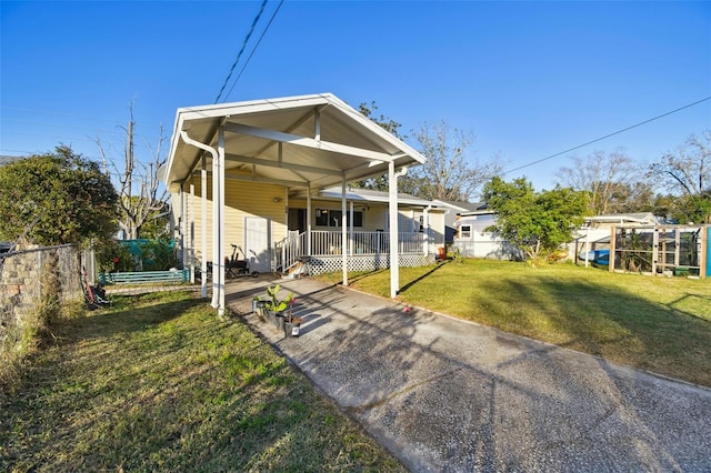 view of front of property featuring covered porch, a front yard, and a carport