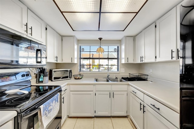 kitchen featuring sink, black appliances, light tile patterned floors, decorative light fixtures, and white cabinetry