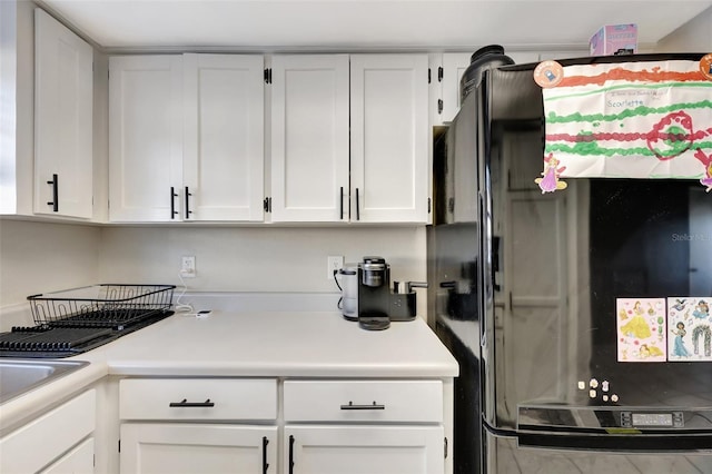 kitchen featuring black refrigerator and white cabinetry