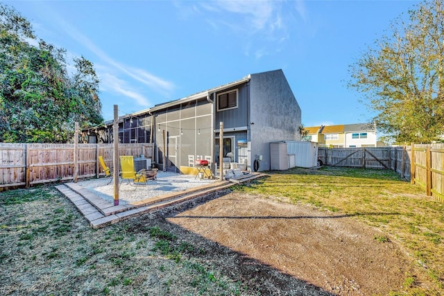 back of house featuring a yard, a patio, and a sunroom