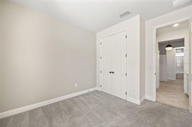 unfurnished bedroom with light carpet and a closet