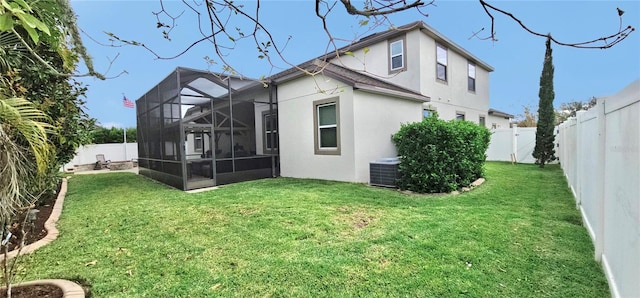 rear view of house with a yard, glass enclosure, and central air condition unit