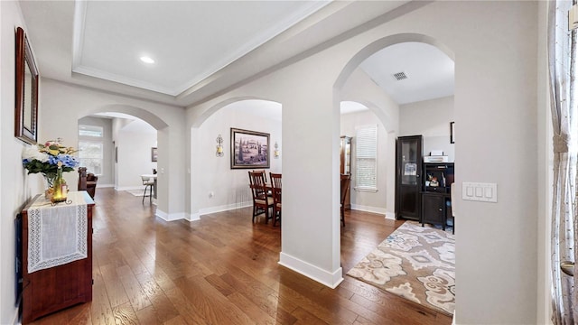 hallway featuring ornamental molding, a raised ceiling, and dark hardwood / wood-style floors