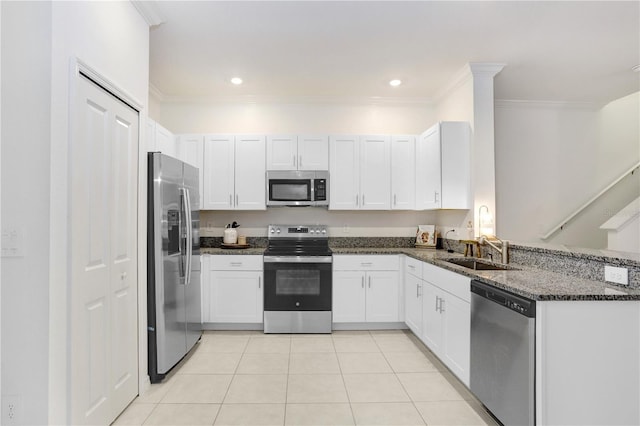 kitchen with sink, appliances with stainless steel finishes, dark stone countertops, white cabinetry, and light tile patterned flooring