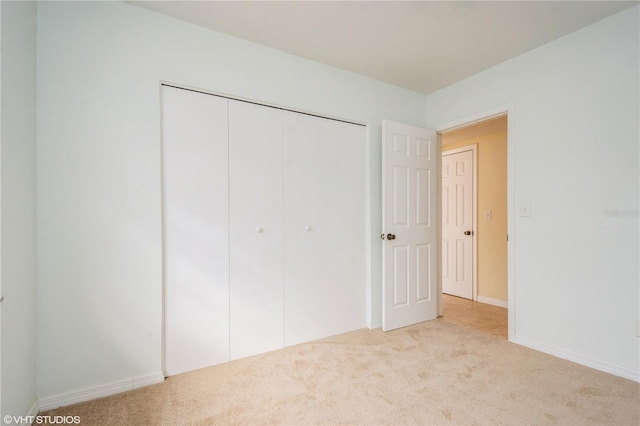 unfurnished bedroom featuring light carpet and a closet