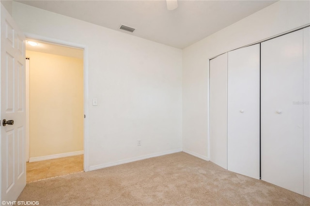 unfurnished bedroom featuring light carpet and a closet