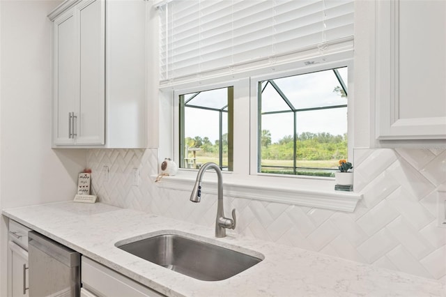 kitchen with dishwasher, backsplash, sink, light stone counters, and white cabinetry