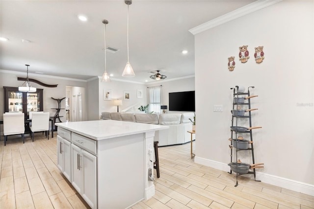 kitchen featuring ceiling fan, a center island, white cabinets, and hanging light fixtures