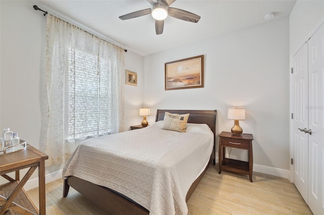 bedroom with ceiling fan, light wood-type flooring, and a closet