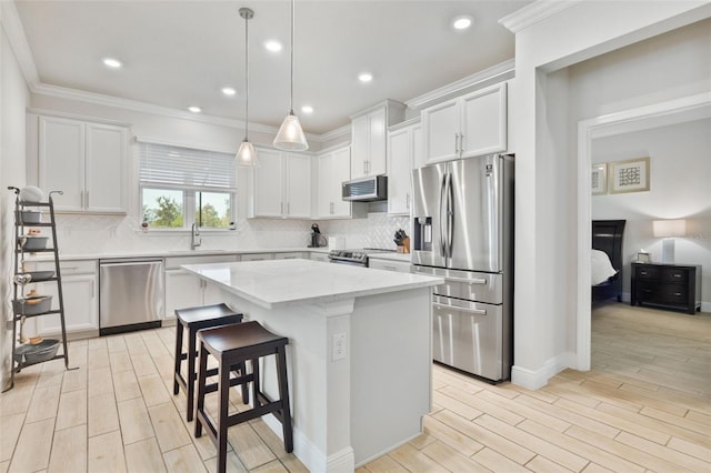 kitchen with white cabinetry, stainless steel appliances, a kitchen island, and pendant lighting