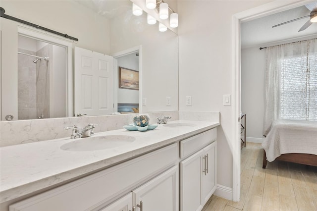 bathroom featuring ceiling fan, vanity, tiled shower, and wood-type flooring