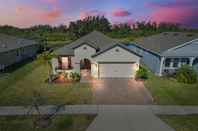 ranch-style home with a garage and a lawn