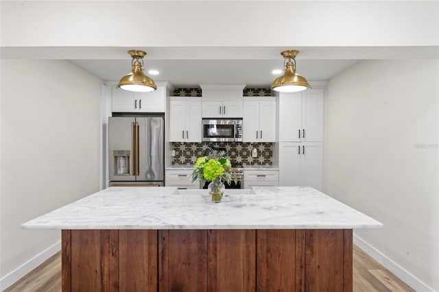 kitchen with white cabinetry, decorative backsplash, stainless steel appliances, and a kitchen island