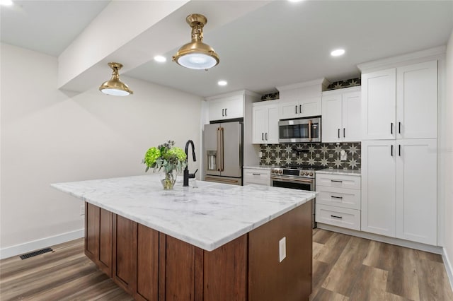 kitchen with appliances with stainless steel finishes, a kitchen island with sink, light stone countertops, white cabinets, and dark hardwood / wood-style flooring