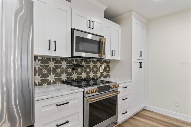 kitchen with tasteful backsplash, stainless steel appliances, light stone countertops, and white cabinets