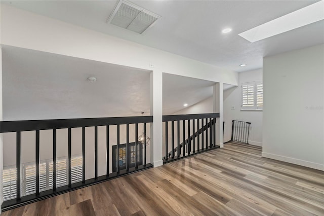 hallway with a skylight and light hardwood / wood-style floors