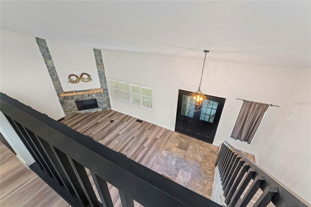 entrance foyer with vaulted ceiling, wood-type flooring, a chandelier, and a fireplace