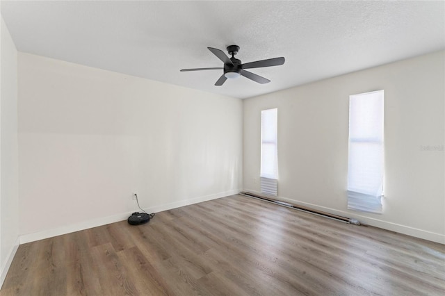 empty room with ceiling fan, a textured ceiling, and light wood-type flooring