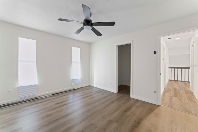 empty room with ceiling fan, a textured ceiling, and light wood-type flooring