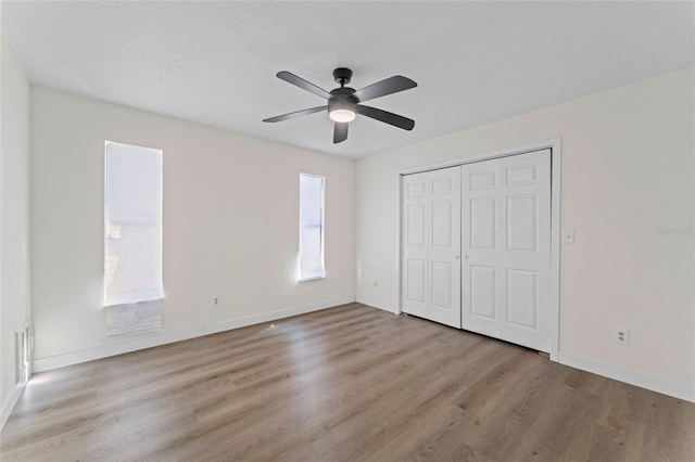 unfurnished bedroom featuring ceiling fan, a closet, and light wood-type flooring