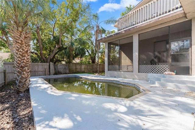 view of swimming pool with a sunroom and a patio area