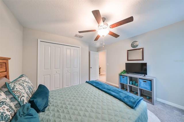 carpeted bedroom with ceiling fan, a textured ceiling, and a closet