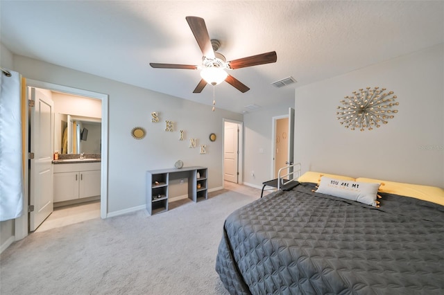 bedroom with connected bathroom, ceiling fan, light carpet, and a textured ceiling