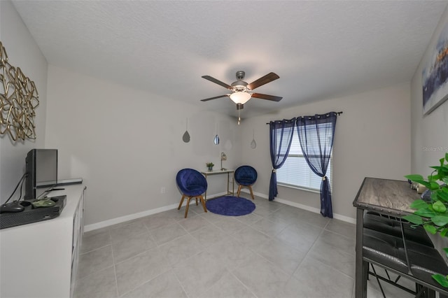 living area featuring ceiling fan, light tile patterned flooring, and a textured ceiling