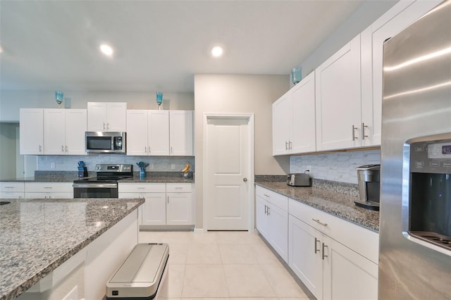 kitchen with white cabinetry, stainless steel appliances, backsplash, stone countertops, and light tile patterned floors