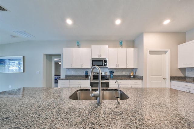 kitchen featuring dark stone counters, sink, appliances with stainless steel finishes, tasteful backsplash, and white cabinetry